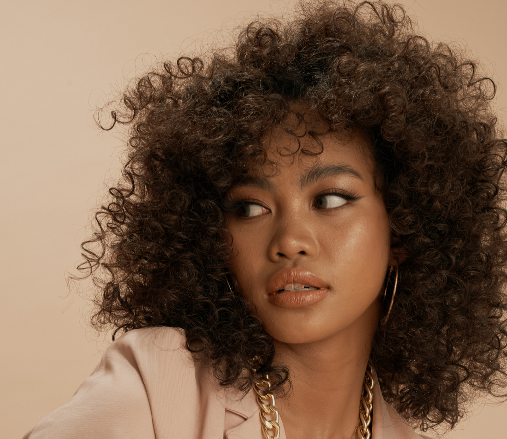 Woman with curly hair against a beige background with text about curly hair being professional.